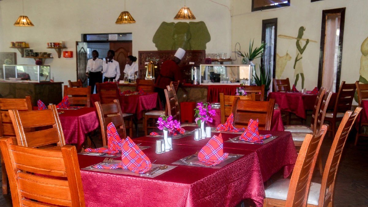 Restaurant dining room with red-clothed tables set for a meal at AA Lodge Amboseli.