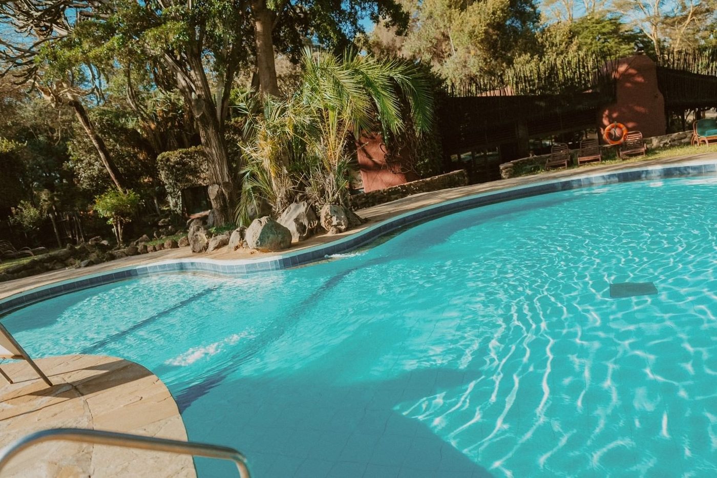 Swimming pool surrounded by palm trees and lawns at Amboseli Serena Safari Lodge.