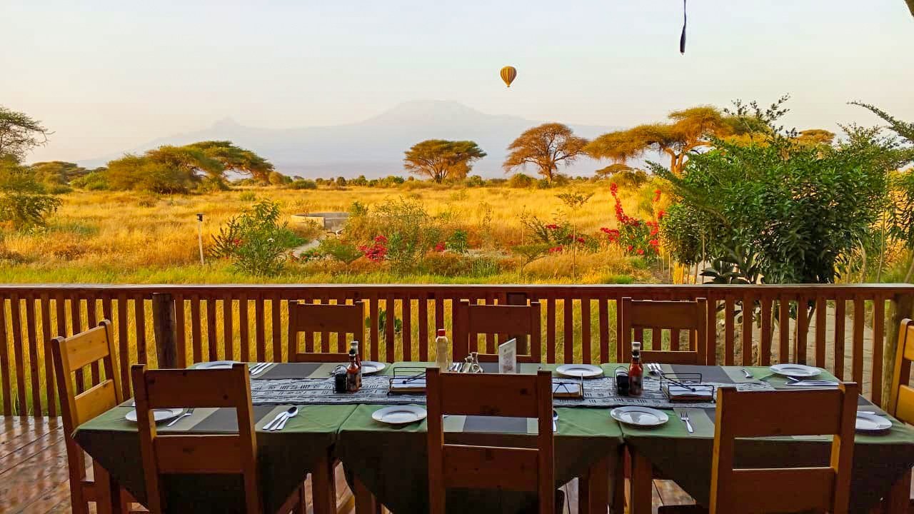 Long dining table set on an open-air deck overlooking the plains at Amboseli Wildebeest Camp.