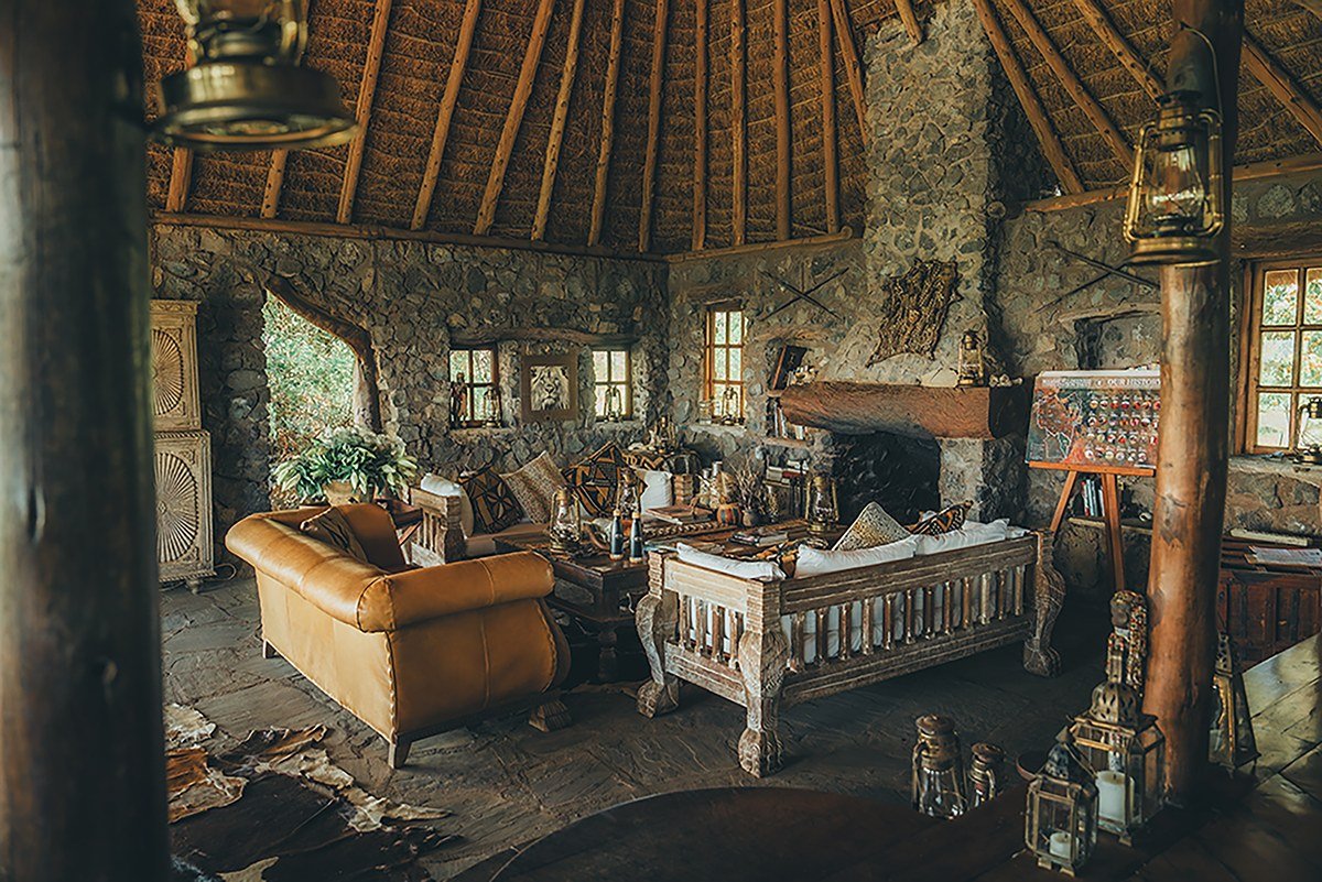 Stone-walled lounge with a fireplace and leather armchairs at Campi ya Kanzi.