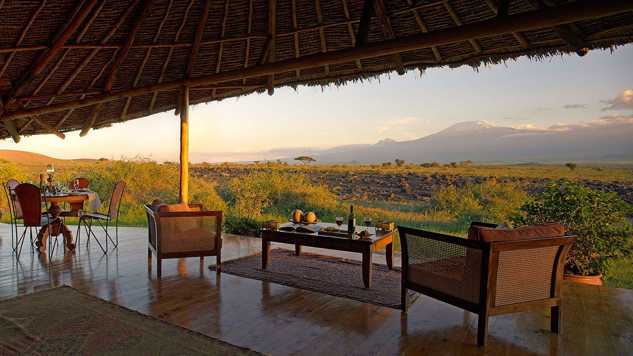 Thatched lounge deck overlooking the plains toward Kilimanjaro at dusk at Elewana Tortilis Camp, Amboseli.