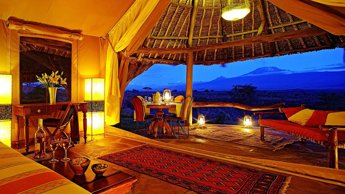 Candlelit deck lounge with Kilimanjaro's silhouette at blue hour at Elewana Tortilis Camp.