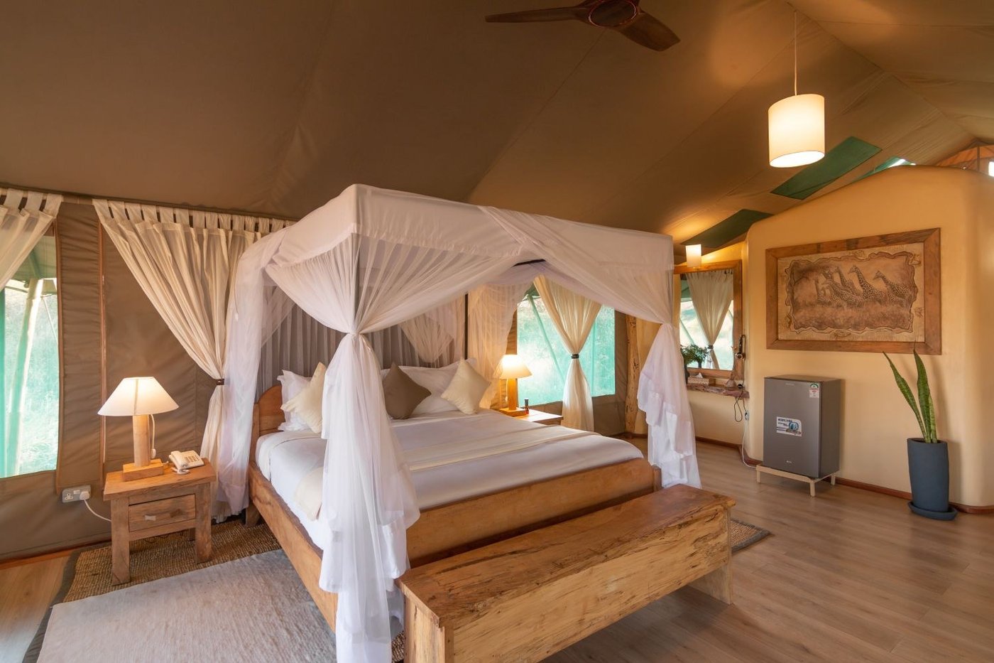 Canopied bed with white netting in a spacious tented room at Kibo Safari Camp.