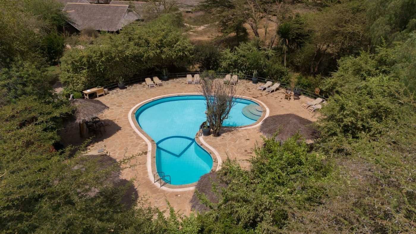 Aerial view of the kidney-shaped pool set among rocks at Kibo Safari Camp.
