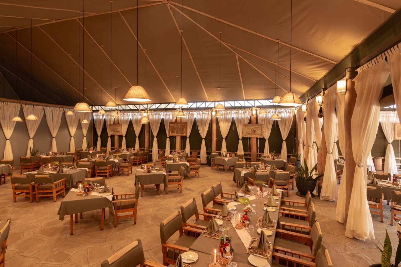 Dining tent set with tables beneath canvas drapes at Kibo Safari Camp.