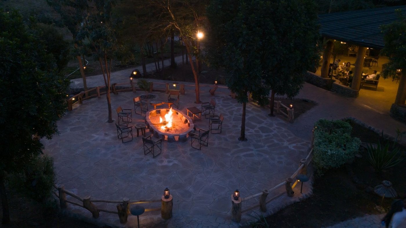 Circular fire pit glowing at night beside the main lodge at Kibo Safari Camp.