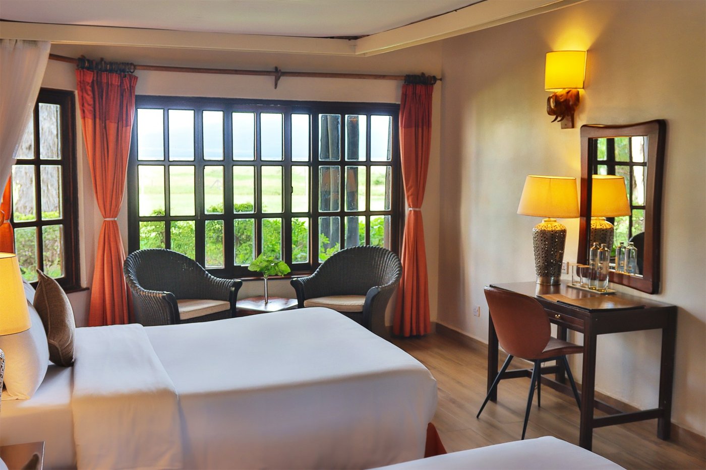 Twin beds with red curtains and a writing desk in a room at Kibo Villa.
