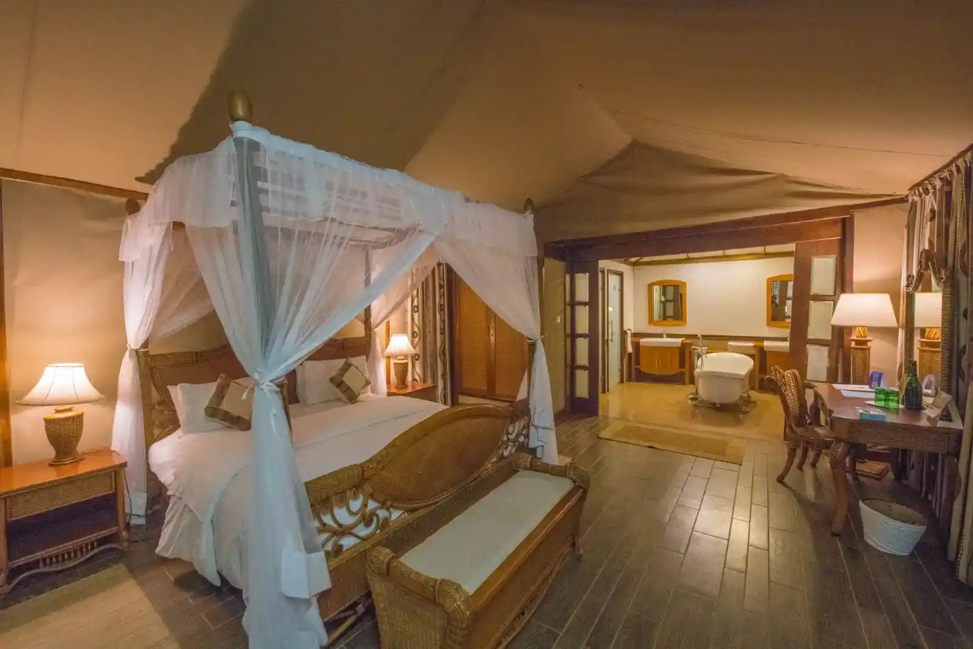 Four-poster bed draped in white netting in a suite at Kilima Safari Camp.
