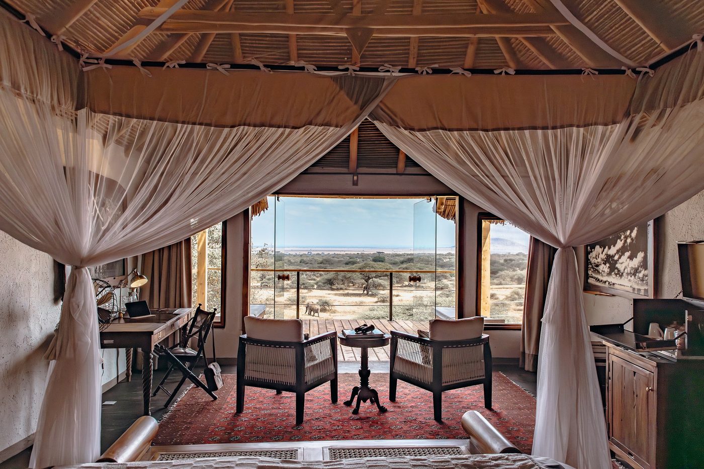 Four-poster bed opening onto a private deck and view at ol Donyo Lodge.