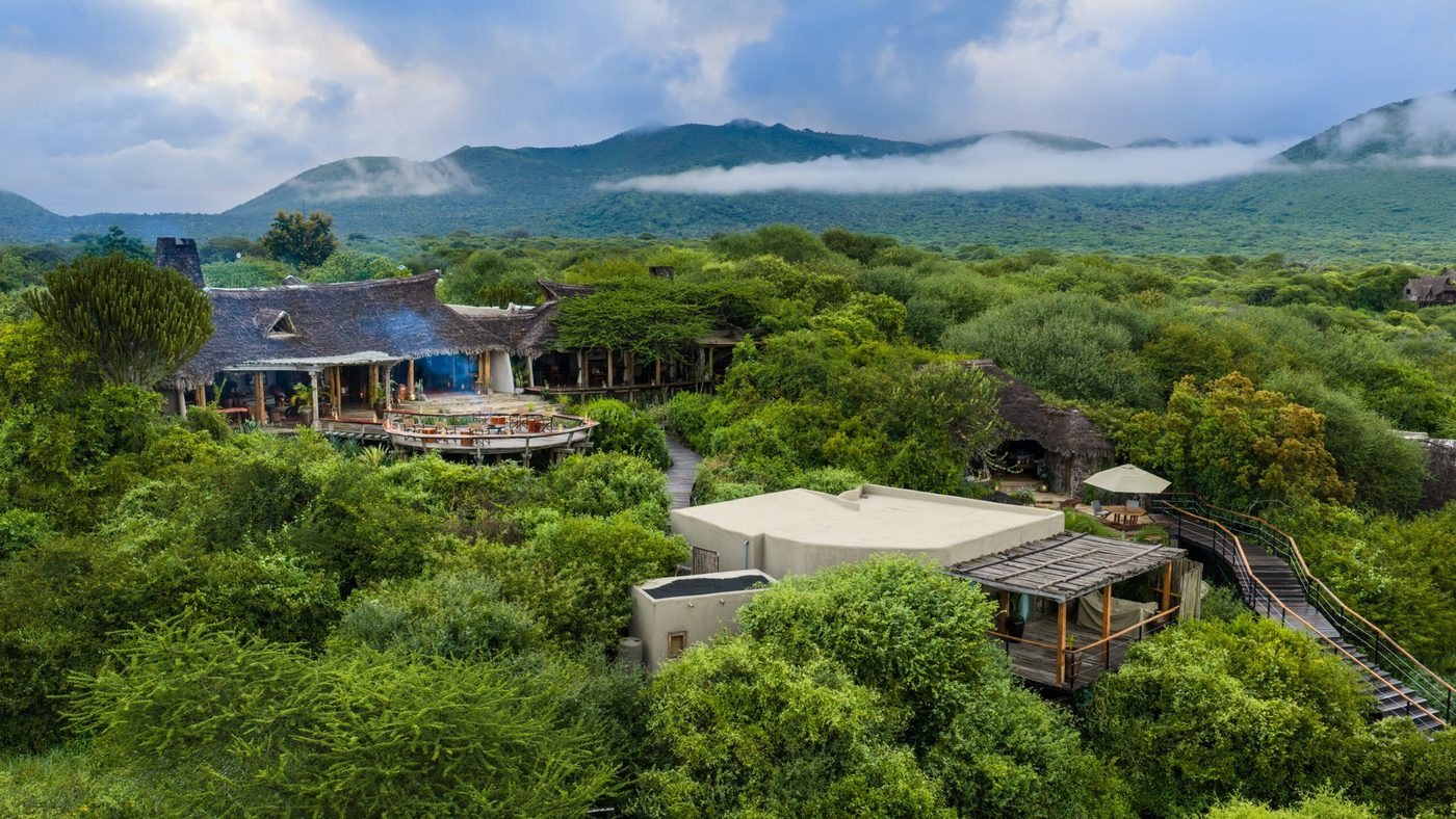 Aerial view of the lodge buildings set among green hillside woodland at ol Donyo Lodge.