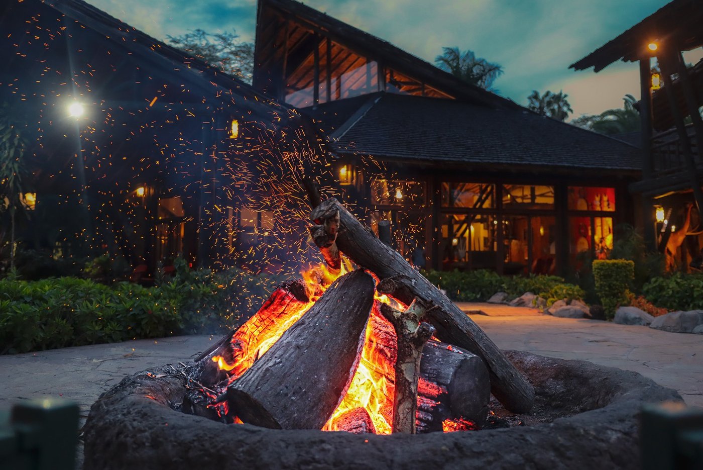 Thatched lodge building lit at night beside a roaring fire pit at Ol Tukai Lodge, Amboseli.