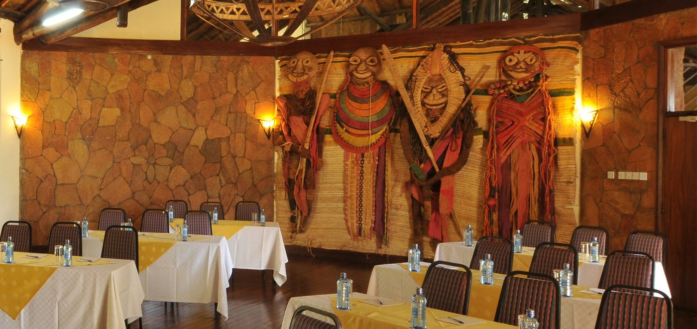 Dining room set with yellow linens beneath tribal wall art at Ol Tukai Lodge.