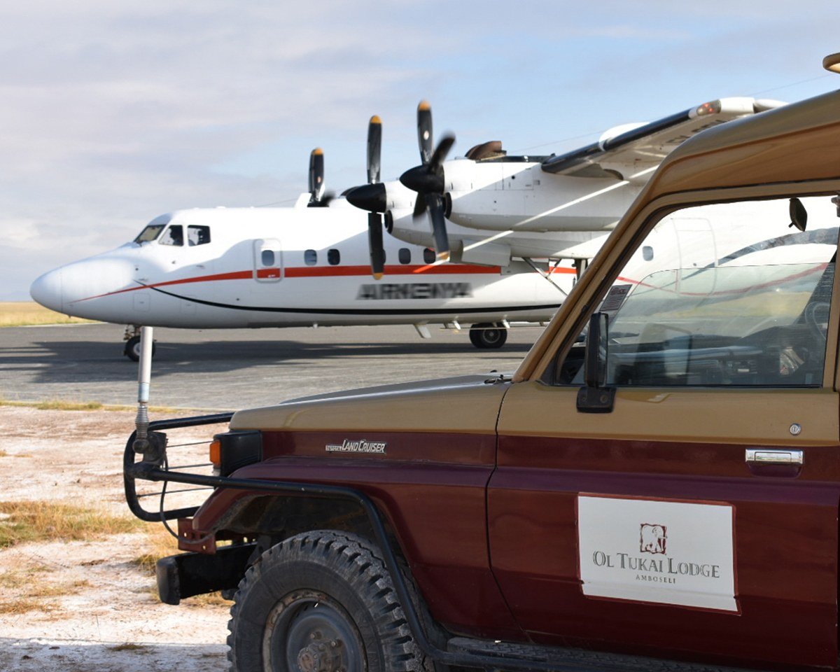 Branded safari vehicle and light aircraft on the airstrip for Ol Tukai Lodge.