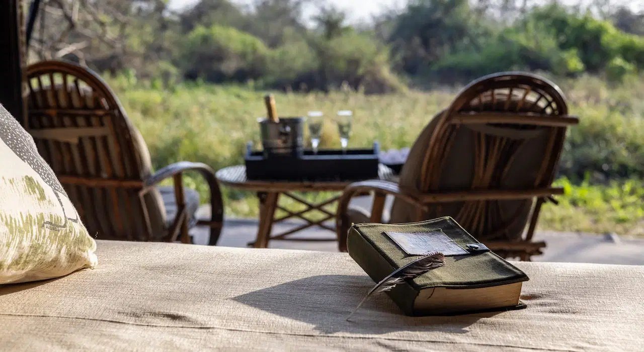 Outdoor seating nook with wicker chairs and a low table at Porini Amboseli Camp.