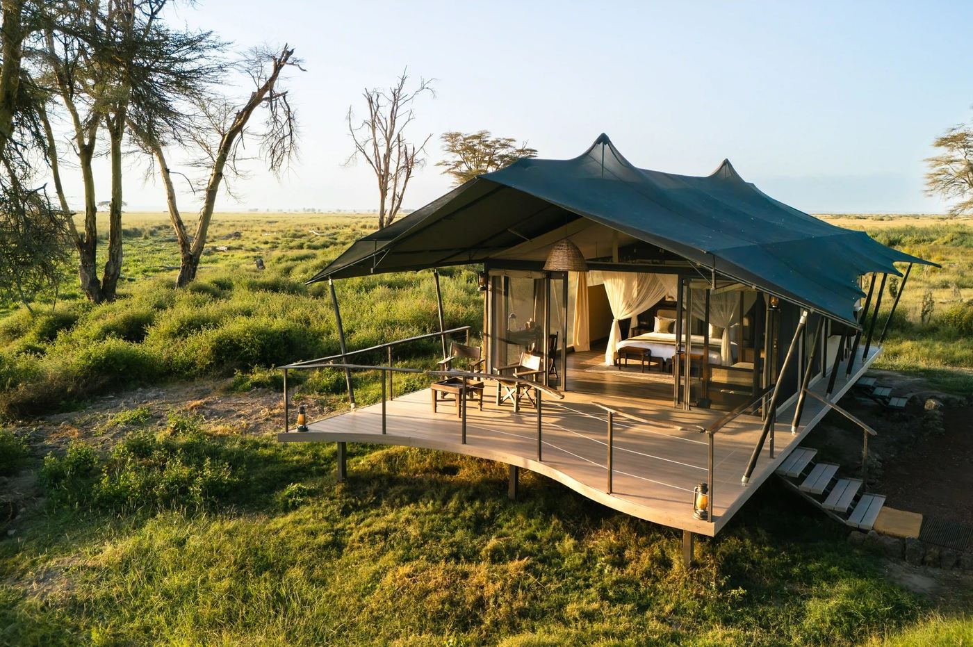 Canvas-walled tent camp on a raised deck amid open grassland at Soroi Amboseli.