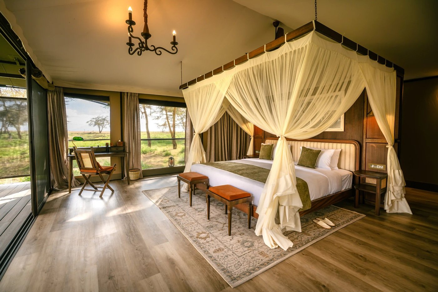 Spacious tent bedroom with a canopy bed and floor-to-ceiling glass at Soroi Amboseli.