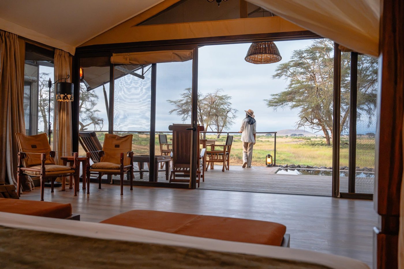 Open-sided lounge tent with wooden furniture facing the plains at Soroi Amboseli.