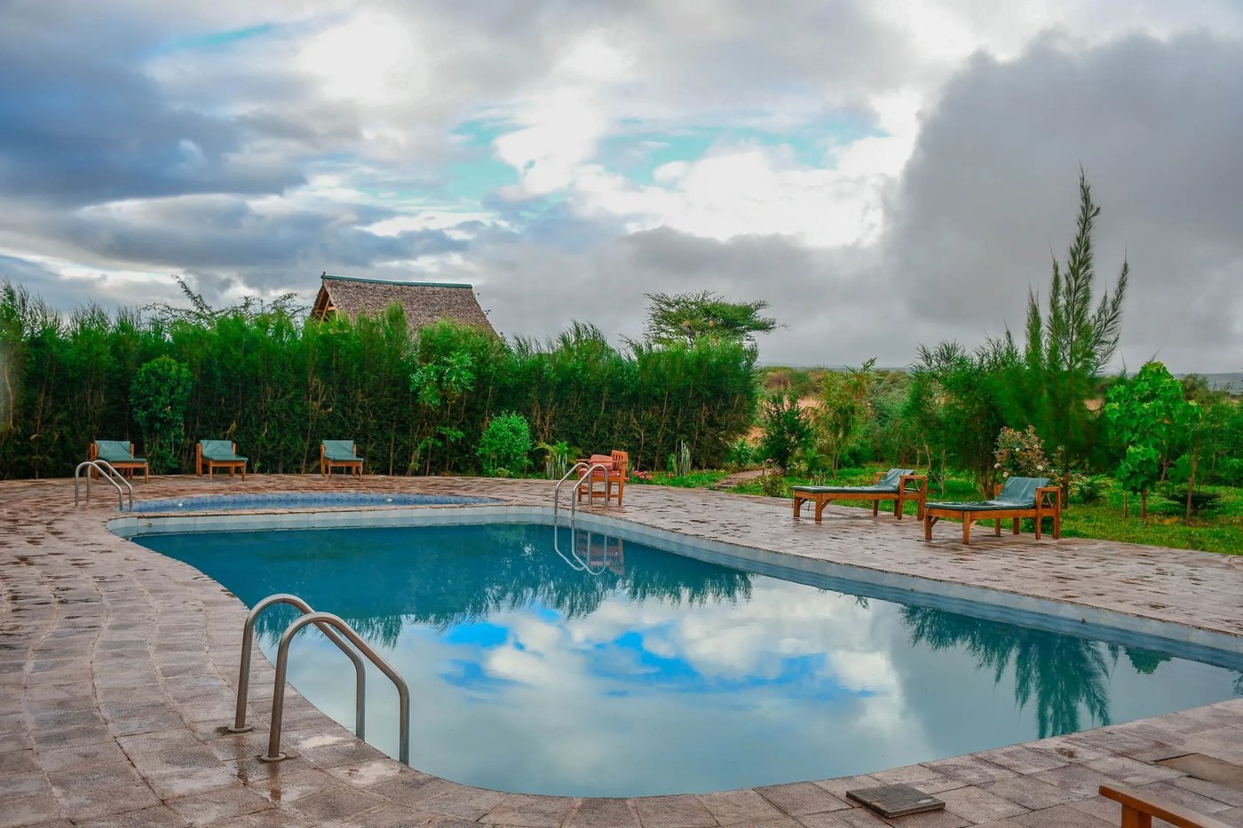 Rectangular swimming pool with loungers beside the lodge at Sungura Safari Camp.