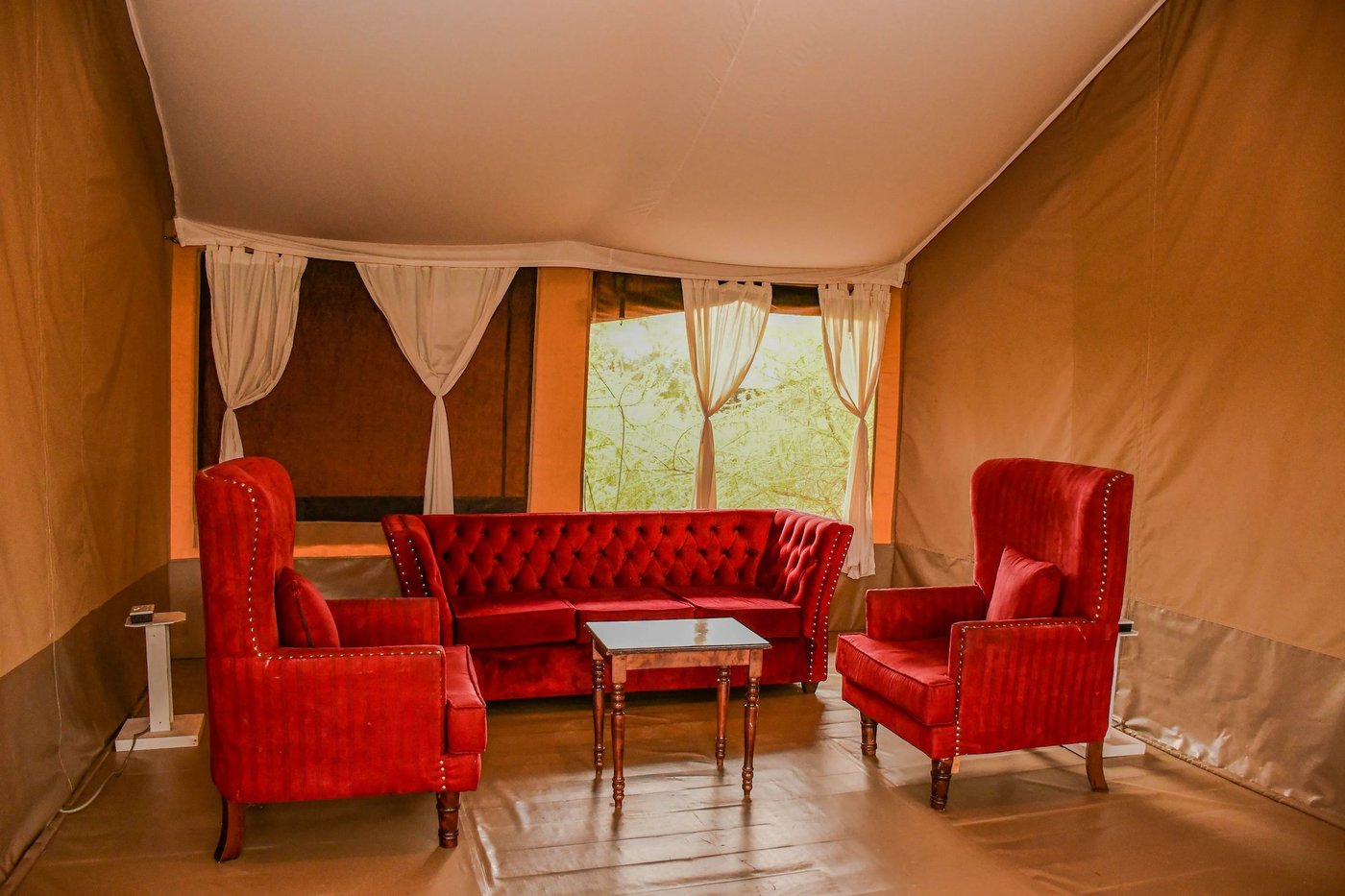 Red armchairs and a sofa in the lodge lounge at Sungura Safari Camp.