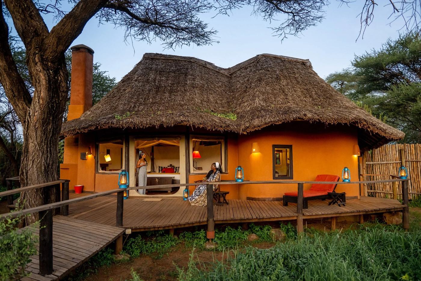 Orange-walled cottage with a thatched roof and private deck at Tawi Lodge.